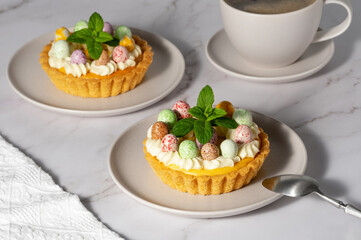 Mini cheesecakes with candy eggs and whipped cream. Pastel colored Easter dessert