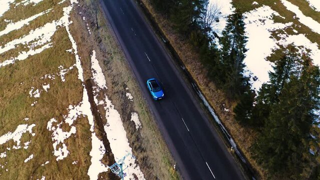 A blue Audi S3 driving along a mountain straight road in winter, cinematic shoot from a drone in the Polish Tatra Mountains.
