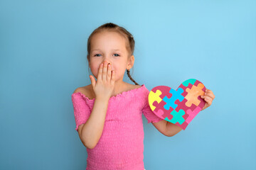 A child shows a heart made of bright colored puzzles and sends an air kiss to people with autism...
