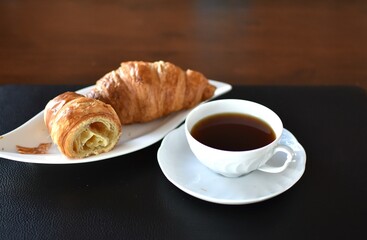 croissant and porcelain cup with tea on a saucer