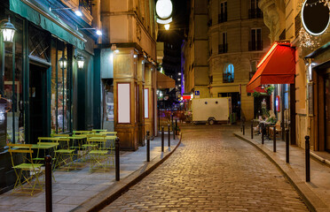 Fototapeta premium Cozy street with tables of cafe in Paris at night, France. Architecture and landmark of Paris. Paris cityscape