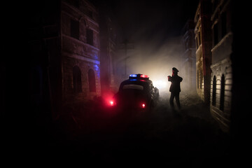 Police raid at night and you are under arrest concept. Silhouette of handcuffs with police car on...