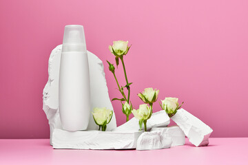 bottle of cream or body lotion with stones and white roses