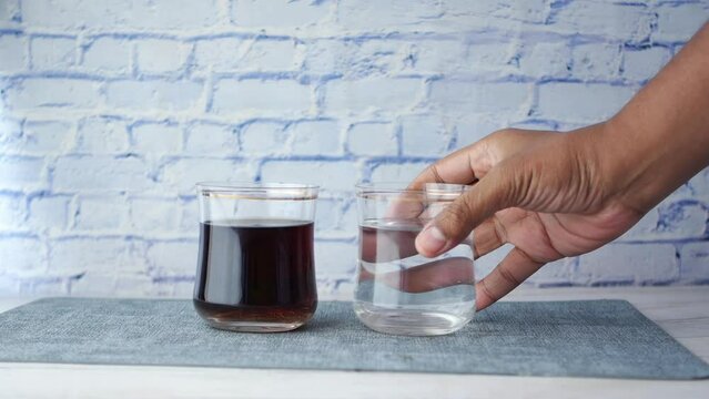 comparing soft drinks with glass of water on table 