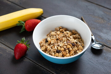 Dry granola in a bowl on wooden table. Healthy breakfast cereals, baked oat honey granola with...
