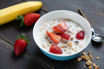 Breakfast bowl with granola and oat milk and fresh strawberries on a wooden table background, closeup view. Healthy food, clean eating, dieting concept