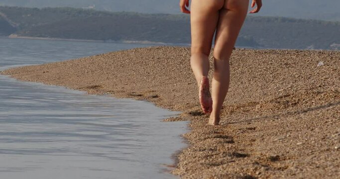 A girl is walking on a pebble beach Zlatni Rat near Bol town, Brač Island, the Adriatic Sea, Croatia