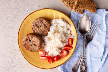 cutlets, rice, tomatoes on a round plate, top view