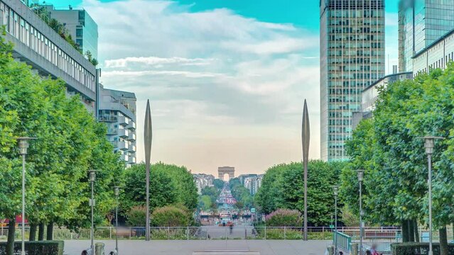 Skyscrapers of La Defense timelapse - Modern business and residential area in Paris, France. Arc de Triomphe with Champs Elysees on background. Green trees, blue cloudy sky at evening