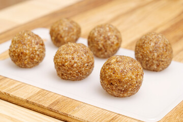 Energyballs candy on a white cutting board lying on a wooden table. 