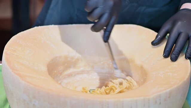 Chef cook preparing spaghetti pasta in a big wheel of parmesan cheese