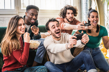 Happy multi ethnic friends sitting on sofa playing video games - Cheerful generation z group having fun with modern technology videogames - Hobby and tech concept - obrazy, fototapety, plakaty