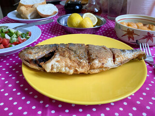 Table with sea bream, salad, lemon and dessert
