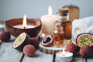 Glass bottles with pure organic essential litchi and passion fruit oil on wooden background. Concept of natural ingredients for beauty treatment, skin care, massage. Exotic fruits extract and essence