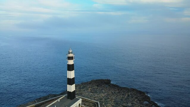 Flying over Artrutx lighthouse in Menorca Spain out to sea with glassy water.