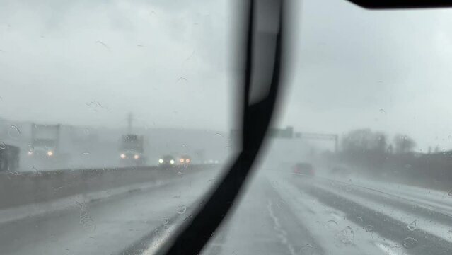 Windshield wiper wipes drops from heavy rain with overcast highway background