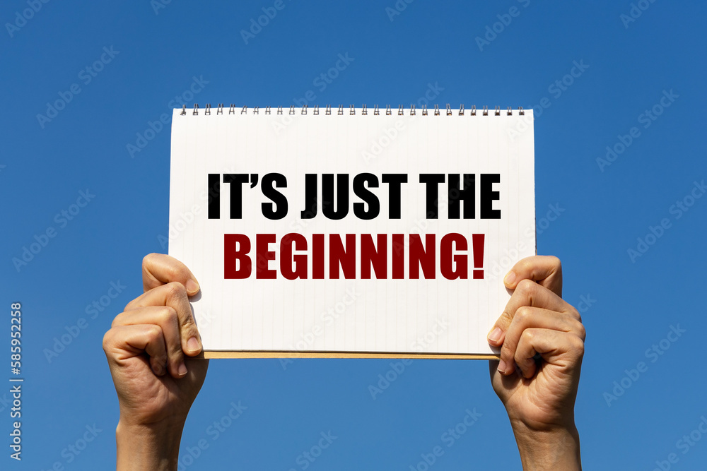 Poster it's just the beginning text on notebook paper held by 2 hands with isolated blue sky background. th