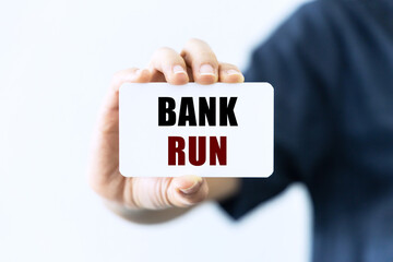 Bank run text on blank business card being held by a woman's hand with blurred background. Business concept about bank run.