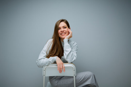 Portrait Of Smiling Woman Sitting On Chair And Leaning On Her Hand, Back View.