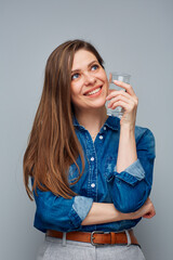 Smiling woman holding water glass looking away, portrait on gray