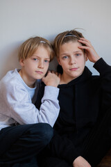 Two happy boys, happy brothers who are seriosly happily together. Brothers stay on grey background. modern tenagers.book cover. one boy in focus other out of focus