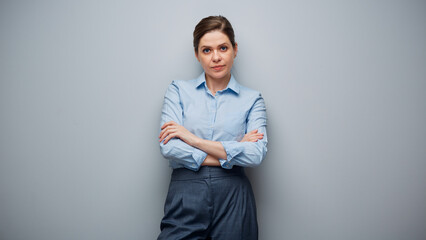 Portrait of serious business woman wearing blue shirt on gray background.