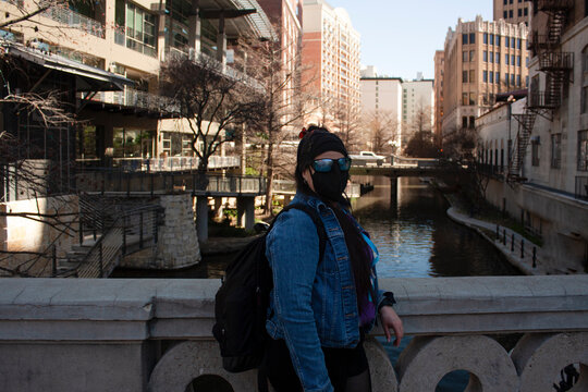 Urban scene in times of pandemic covid19 Caucasian Latina tourist woman takes a break on the streets at the edge of River walk wearing a mask to prevent contagion