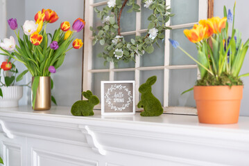 White mantel decorated for spring with colorful tulips and bunnies