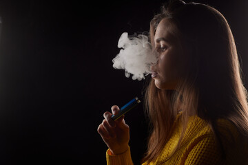 young girl smokes a vape close-up on a dark background