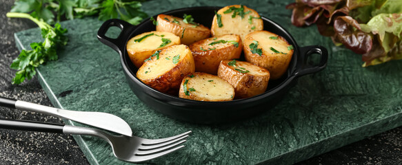 Frying pan of tasty fried potatoes with parsley on table