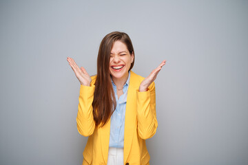 Excited woman in yellow jacket on gray background.