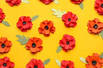 Paper poppy flowers with leaves on yellow background