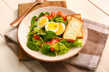 Plate of delicious salad with boiled eggs and salmon on white wooden background