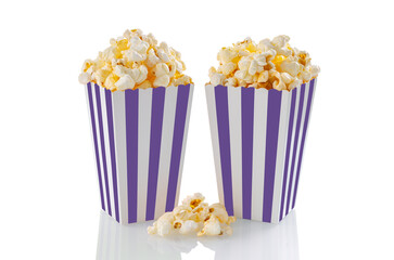 Two purple white striped carton buckets with tasty cheese popcorn, isolated on white background. Box with scattering of popcorn grains. Movies, cinema and entertainment concept. © katyamaximenko