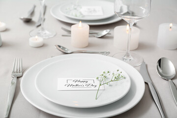 Setting for Mother's Day celebration with gypsophila flowers and burning candles on table