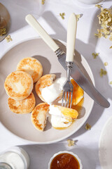 Plate of tasty cottage cheese pancakes with sour cream and jam on light table, closeup