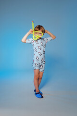 Happy cute boy 6 years old wearing a swimsuit and mask at the blue background