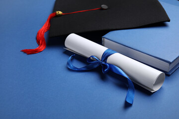 Diploma with ribbon and graduation hat on blue background