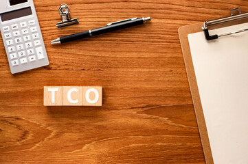 There is wood cube with the word TCO.It is an abbreviation for Total Cost of Ownership as eye-catching image.