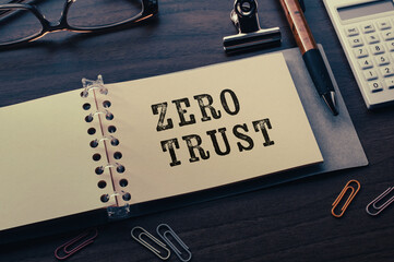 There is note book with the word Zero trust on a laptop. It is an eye-catching image.
