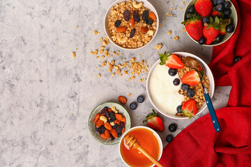 Bowls of tasty granola with yogurt, honey and berries on grunge background