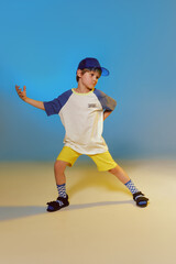 Cheerful emotional boy in a cap at blue and yellow color studio background