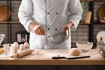 Male chef making dough for pasta at table in kitchen, closeup