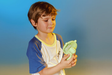 Cheerful boy with a fan at blue and yellow color studio background