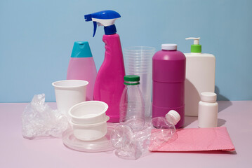 Still life of different types of plastic packaging of purple, pink and blue colors, on blue and purple background, studio lighting