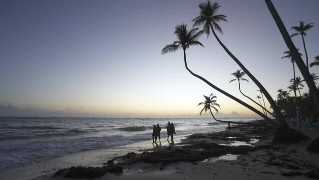 People, waves lapping on the beach and palm trees at sunrise, Bavaro Beach, Punta Cana, Dominican Republic, West Indies, Caribbean, Central America