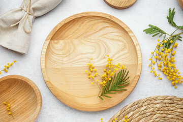 Composition with clean wooden dishes, napkin and mimosa flowers on white grunge table
