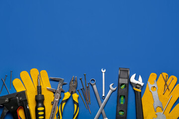 Different construction tools and gloves on blue background