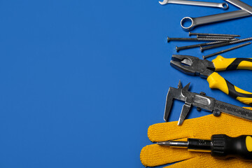 Different construction tools and gloves on blue background
