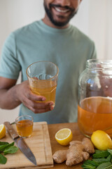 Young black man making homemade kombucha drink, flavoured with lemon and mint, healthy drink, organic probiotic beverage